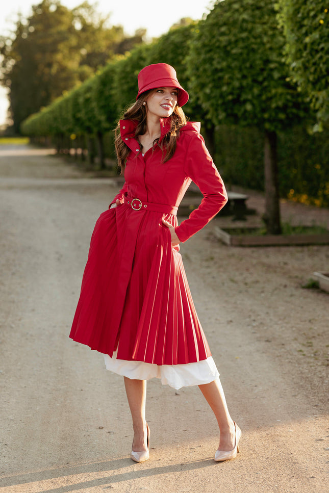 Woman in a red softshell cot and a red hat standing on a road with greenery in the background