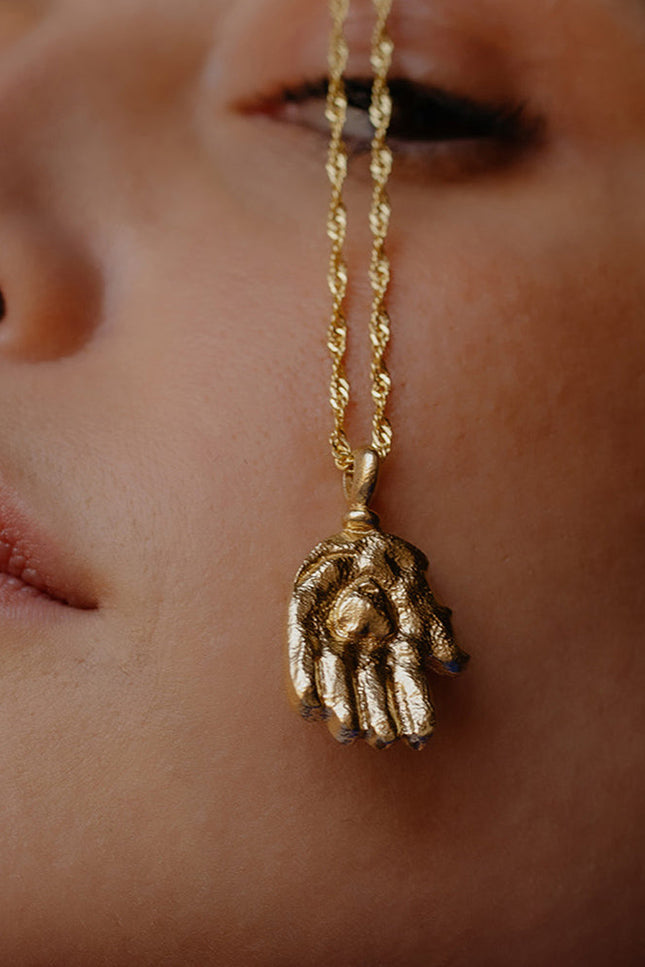 A close-up image of a person wearing a  Sculpted Hand Charm Pendant By arvino
