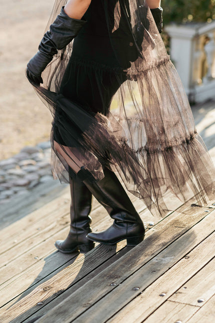 Model wearing a long black tulle dress on a wooden deck