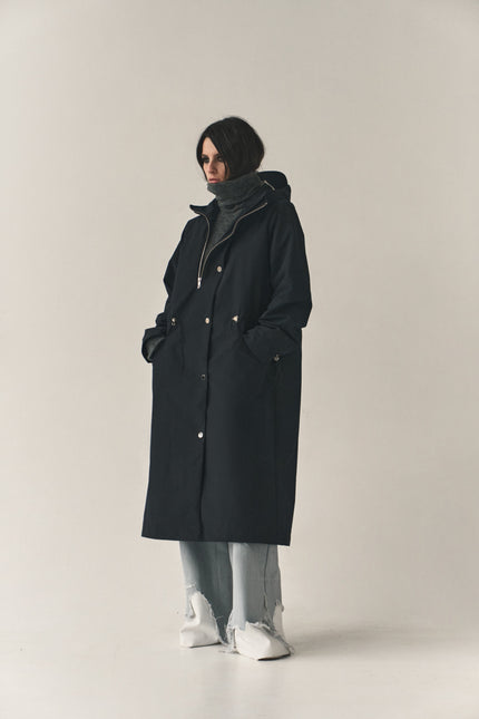 Person wearing a black coat on a plain background