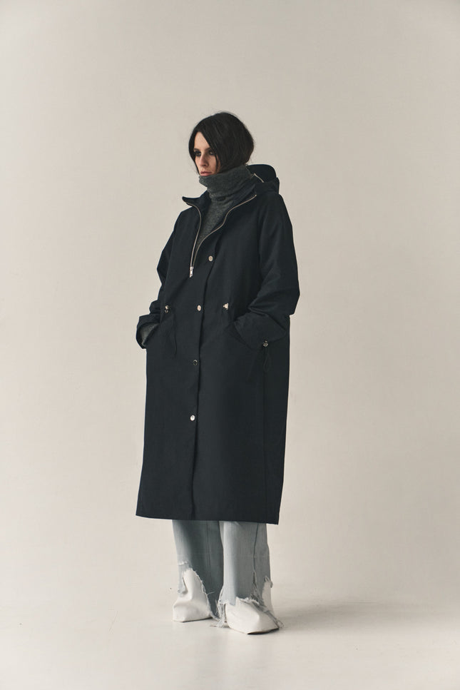 Person wearing a black coat on a plain background
