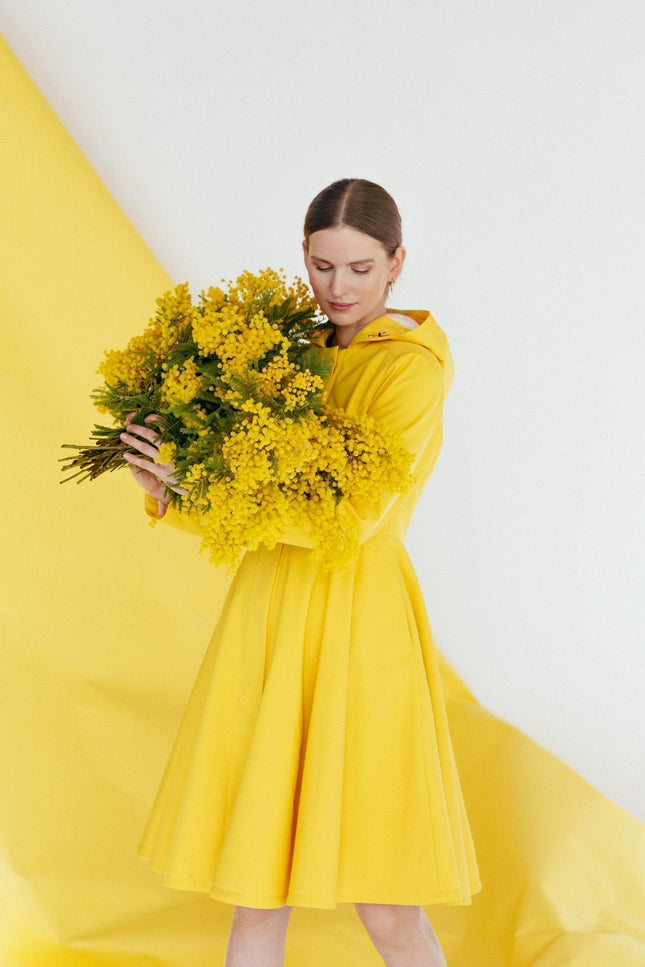 Model wearing Yellow Sun coat – cheerful yellow waterproof coat with adjustable hood and feminine silhouette.