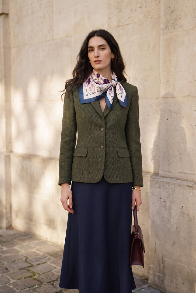 Model wearing NINA HO ILLUSTRATION Angel Flower Blessing silk scarf with a beige skirt and dark blazer in an urban street setting.