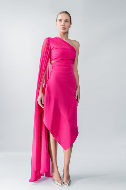 Woman wearing a vibrant pink one-shoulder dress with a cape on a white background