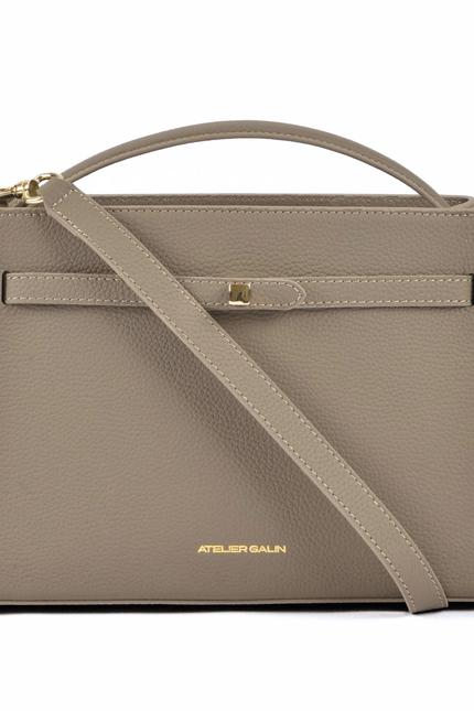 Beige atelier galin cube lock handbag with a shoulder strap on a white background
