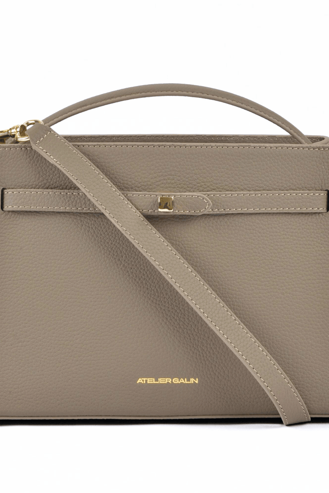 Beige atelier galin cube lock handbag with a shoulder strap on a white background