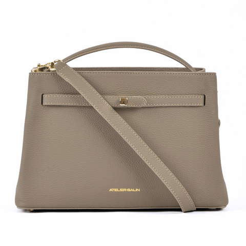 Beige atelier galin cube lock handbag with a shoulder strap on a white background