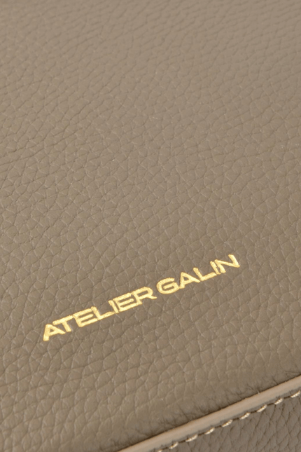 Close-up of a brown leather product with 'Atelier Galin' branding.