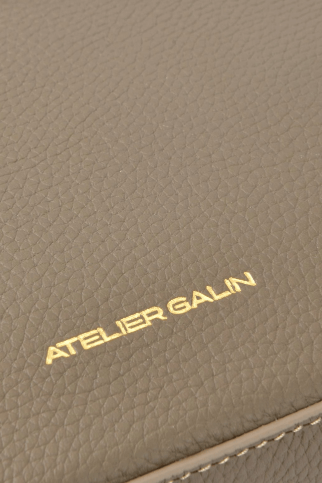 Close-up of a brown leather product with 'Atelier Galin' branding.