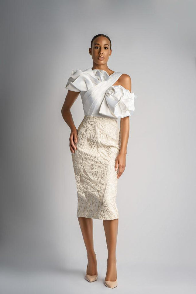 A WOMAN WEARING A BOW DETAIL WHITE LACE MIDI DRESS POSING AGAINST LIGHT GREY BACKGROUND - ANITABEL