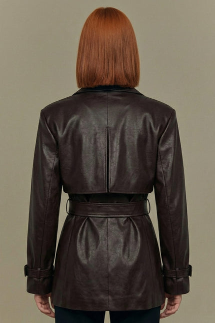 Person wearing a brown leather jacket against a beige background