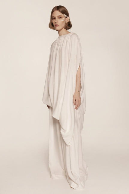 Woman wearing a flowing white dress on a plain background