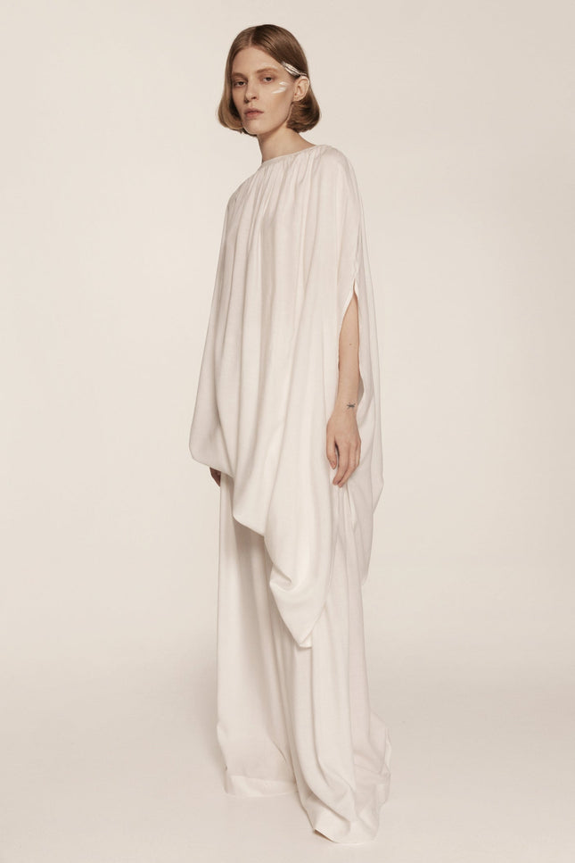 Woman wearing a flowing white dress on a plain background
