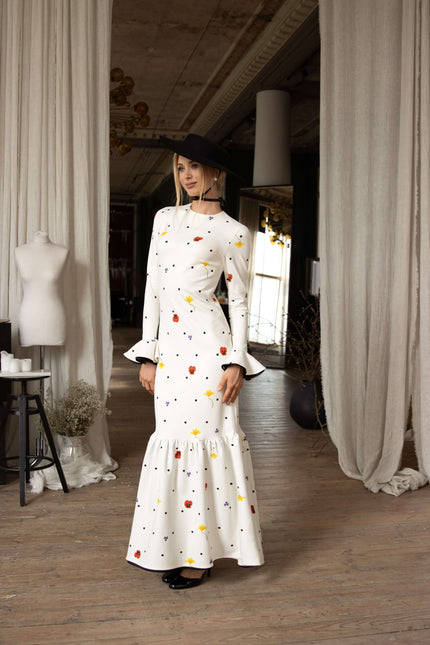 White viscose maxi dress with colorful floral accents and tiny black polka dots, ruffled hemline, and feminine flowing design.