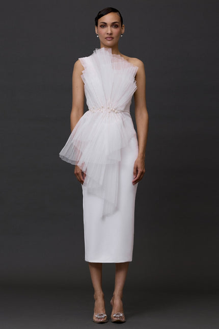 A model wearing a white, tiered, ruffled mini dress with sleeveless top and a flat, platform heel.
