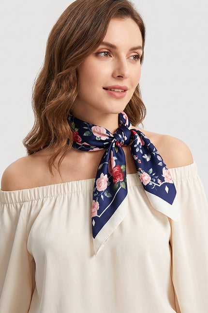 Romantic model with wavy hair wearing a dark blue silk neck scarf with a rose print, off-shoulder style.