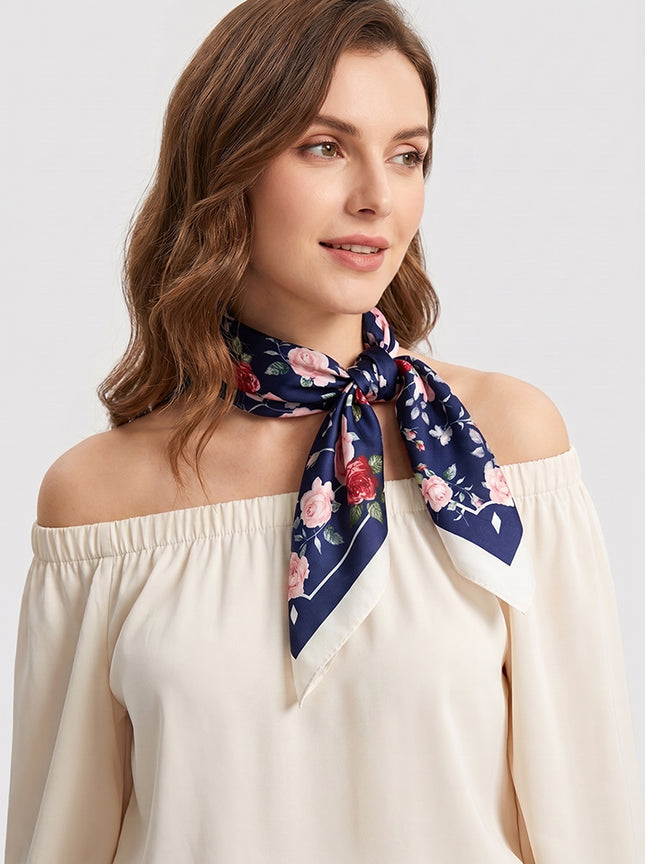 Romantic model with wavy hair wearing a dark blue silk neck scarf with a rose print, off-shoulder style.