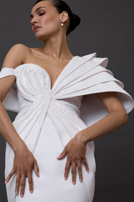 Woman wearing a white dress with a unique design on a dark background