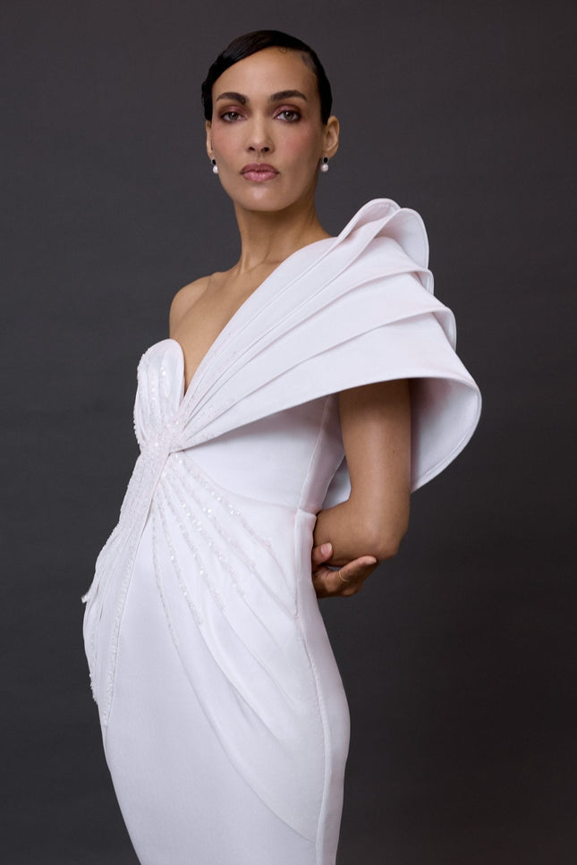 Woman wearing a white dress with a unique design on a dark background