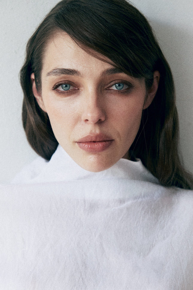 Woman wearing a white turtleneck against a plain background