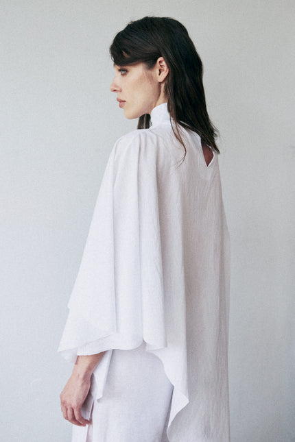 Woman wearing a white blouse against a plain background