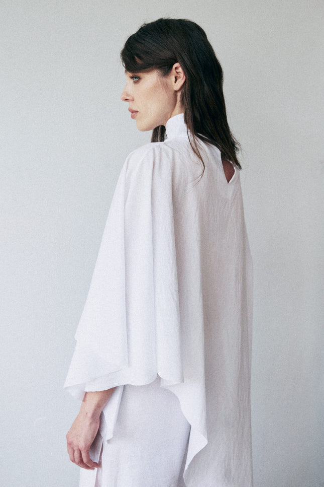 Woman wearing a white blouse against a plain background