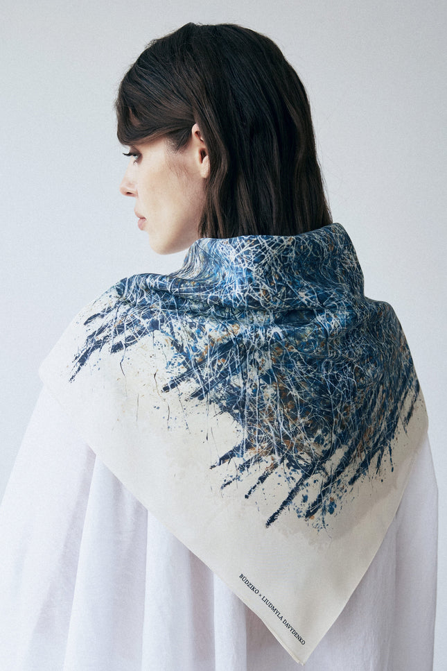 Woman wearing a blue and beige patterned scarf on a white background