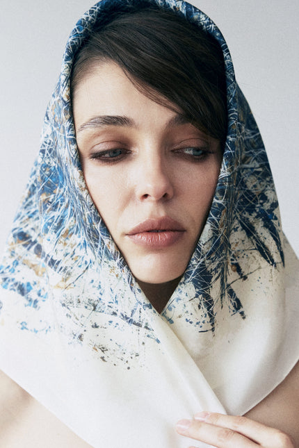 Woman wearing a blue and white patterned headscarf on a plain background