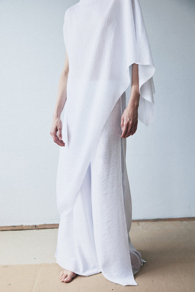 Person wearing a flowing white garment against a plain background