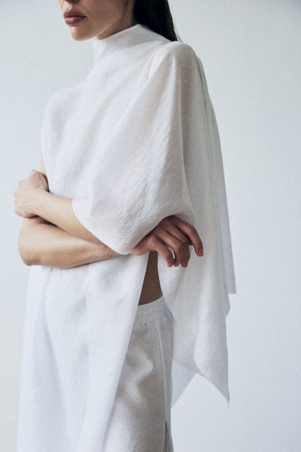 Person wearing a white poncho over a plain background