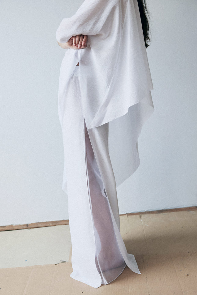 Person wearing a flowing white garment against a plain background