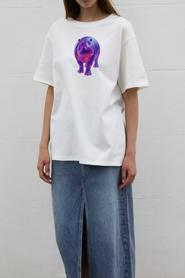 Front view of the SOUR FIGS Iridescent Hippo Print Unisex T-Shirt in White, worn loose with a blue denim skirt to show its oversized fit.