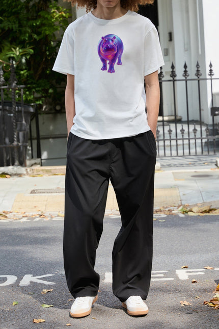 Full-length front view of a model wearing the SOUR FIGS white unisex hippo print T-shirt with black trousers and white trainers.