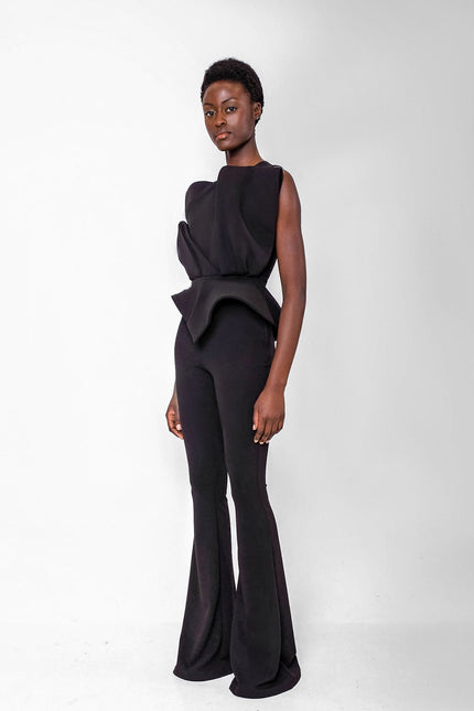 Person wearing a black touser set with a peplum top on a white background