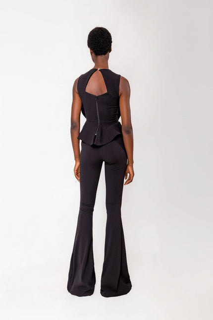 Person wearing a black touser set with a peplum top on a white background