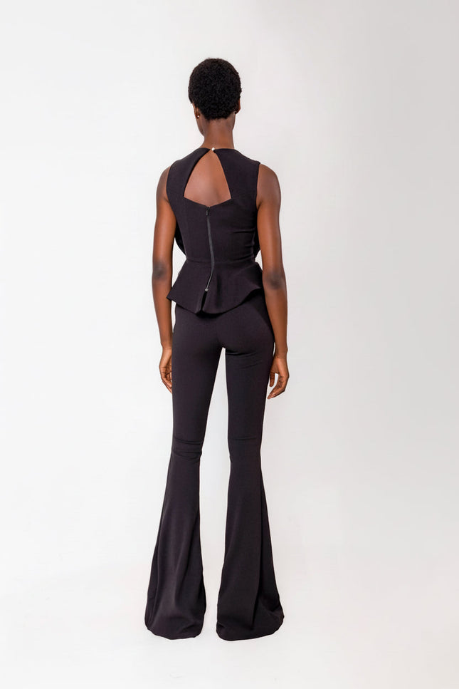 Person wearing a black touser set with a peplum top on a white background
