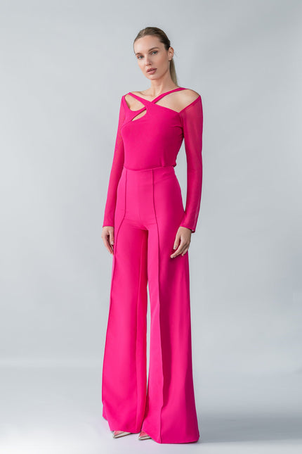 Model wearing a bright pink one-shoulder top and trouser  set on a gray background