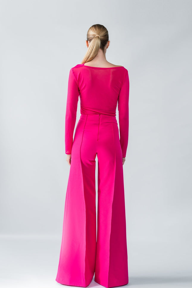 Model wearing a bright pink one-shoulder top and trouser  set on a gray background