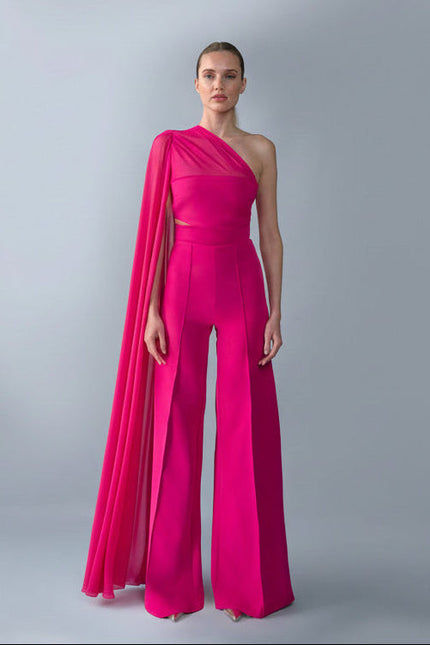 Model wearing a bright pink one-shoulder top and trouser  set with a draped effect on a gray background