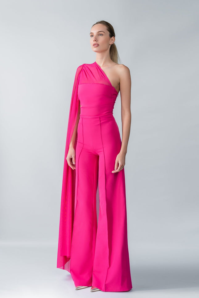 Model wearing a bright pink one-shoulder top and trouser  set with a draped effect on a gray background