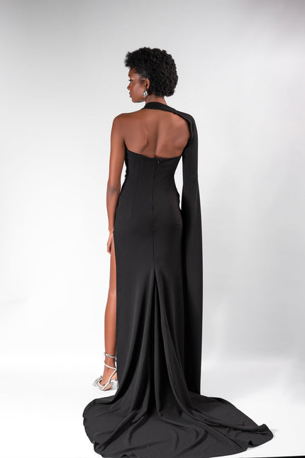 A woman wearing a long  black  dress by Anitabel, posed against a light grey background.