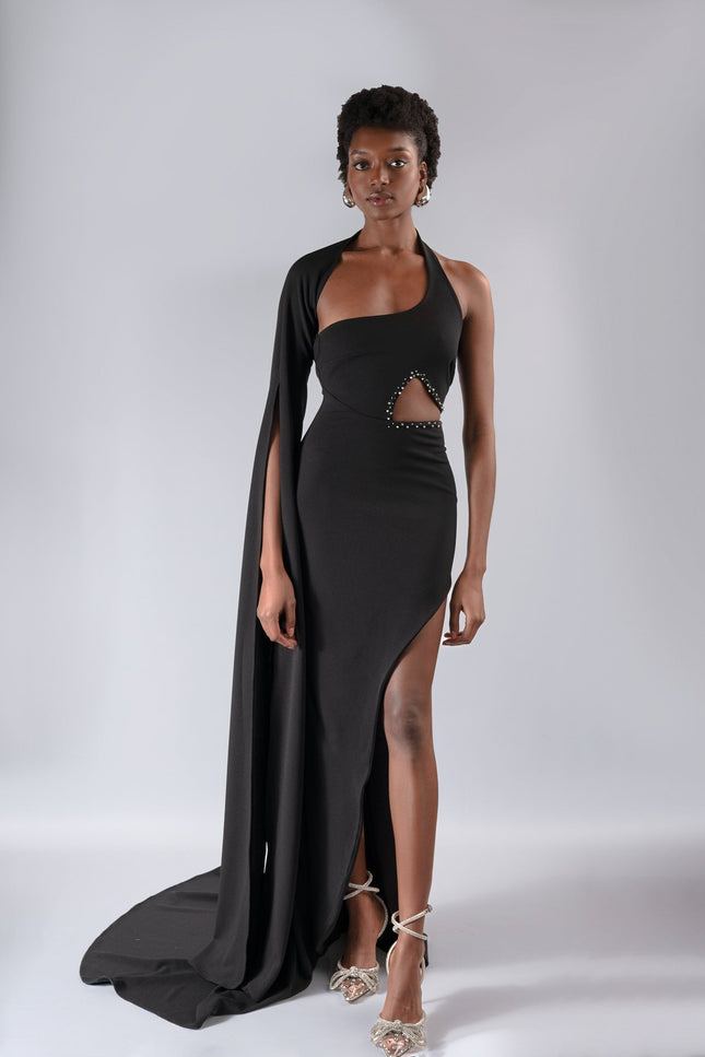 A woman wearing a long  black  dress by Anitabel, posed against a light grey background.
