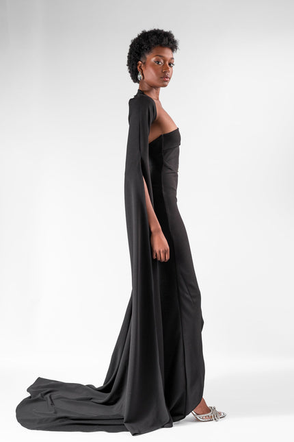 A woman wearing a long  black  dress by Anitabel, posed against a light grey background.