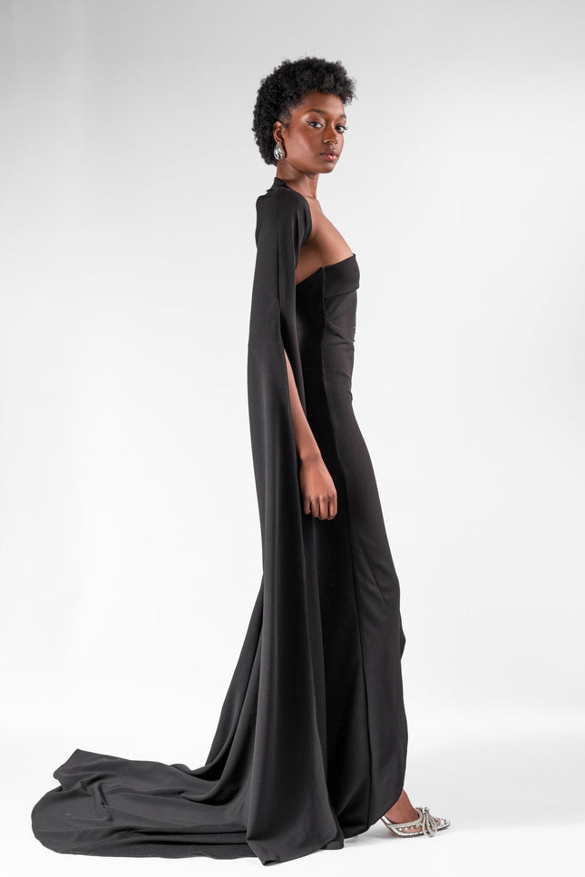 A woman wearing a long  black  dress by Anitabel, posed against a light grey background.