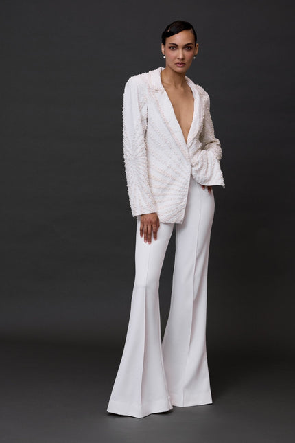 A model wearing white Nirvana Pants, which are visibly flared and have a wide leg style.