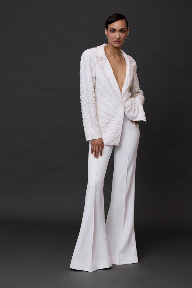 A model wearing white Nirvana Pants, which are visibly flared and have a wide leg style.
