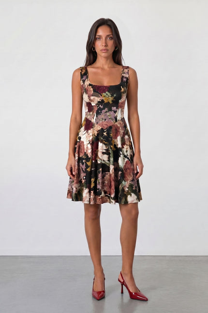 A woman faces forward against a white background, wearing the Sarvin Golha Floral Corset Dress with a flared skater skirt and red pointed-toe heels, her arms relaxed at her sides.