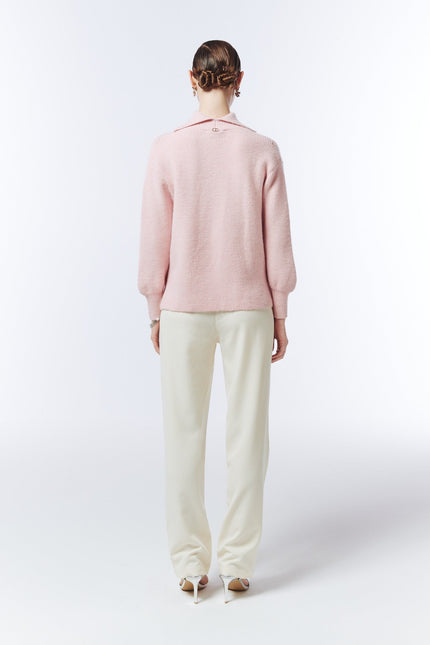 Blush pink pointelle-detail jumper, back view on model showing the plain knit back, high neckline and ribbed cuffs.