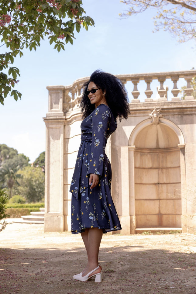 Woman wearing the Meadow Dream midi dress with soft flowing skirt, open shoulder detail, and long sleeves