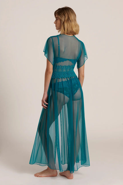 Back view of a model wearing a long, teal green mesh robe, posing in a studio